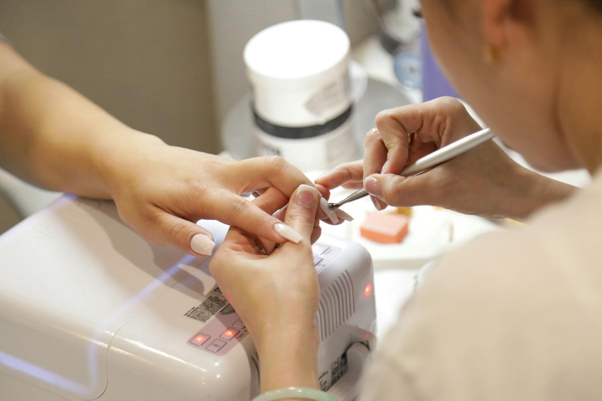 Manicure aan een nageltafel, naast een lamp om gellak uit te harden