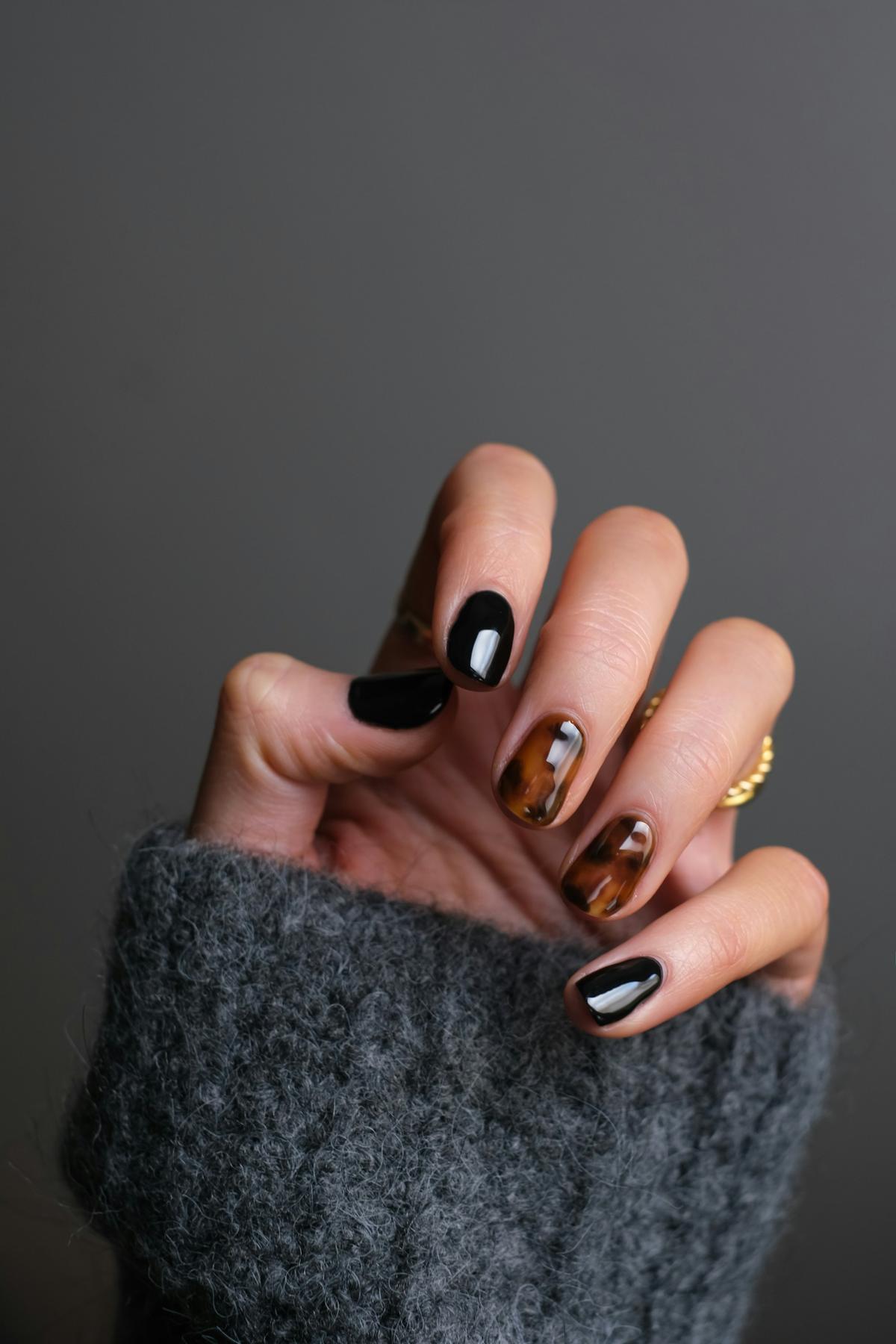 Hand met zwarte en schildpadmotief nagels